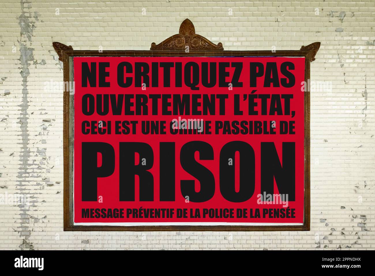 Gros plan sur un panneau d'affichage dans une station de métro parisienne avec un message en français signifiant en anglais 'ne pas critiquer ouvertement l'état, c'est un crime pu Banque D'Images
