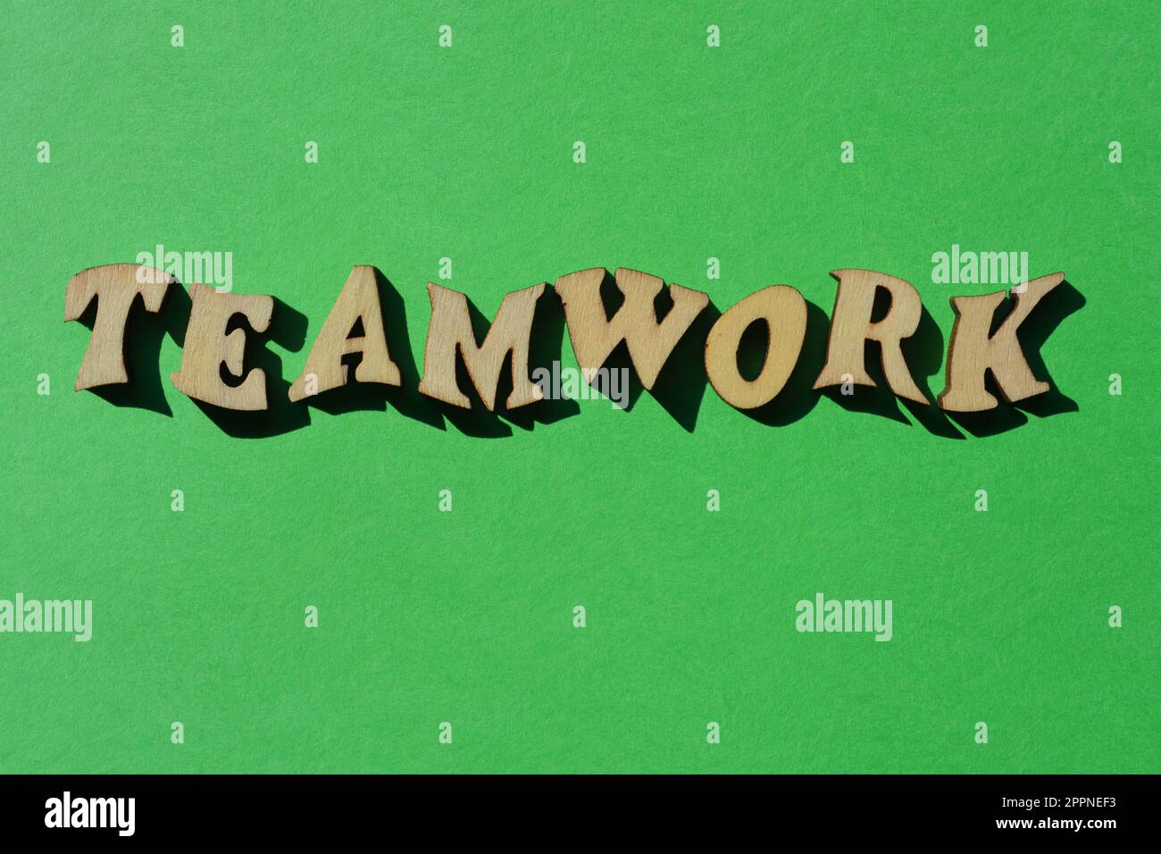 Travail d'équipe, mot en lettres de l'alphabet en bois isolées sur fond vert clair Banque D'Images