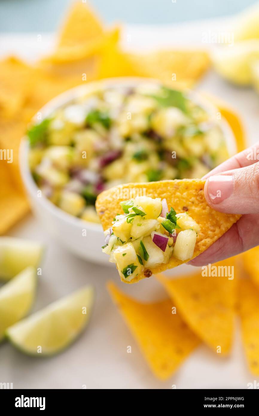 Ananas frais, oignon rouge et salsa de jalapeno dans un bol avec des chips de tortilla en étant scopé avec une puce Banque D'Images