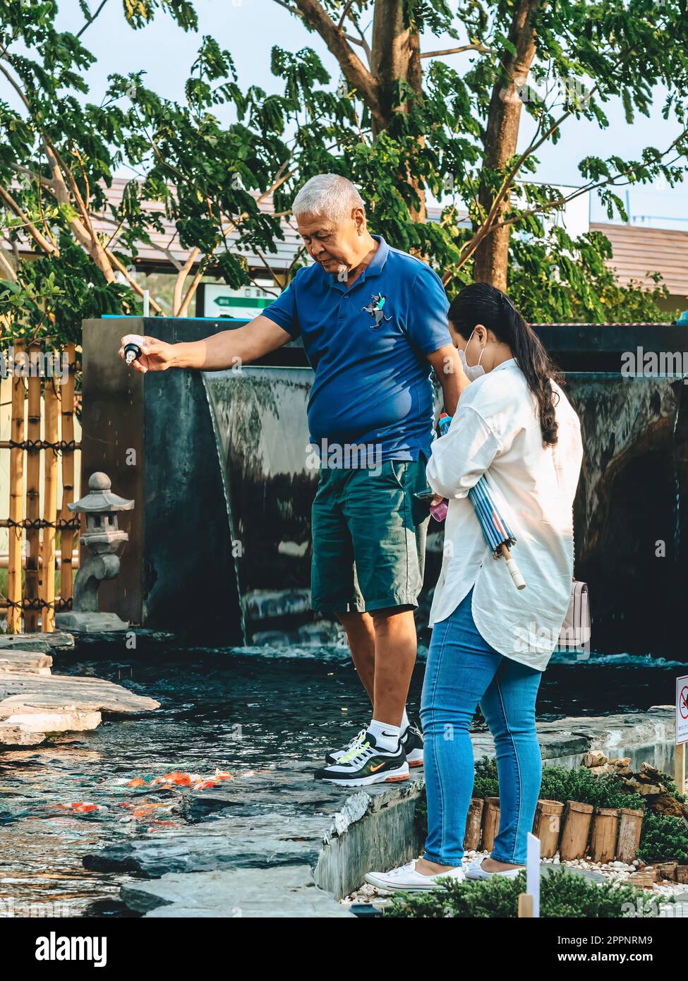 KANCHANABURI -THAÏLANDE, 30 MARS 2023 : touristes non identifiés viennent visiter et nourrir koi ou carpe fantaisie dans un petit étang avec beau jardin décoré Banque D'Images
