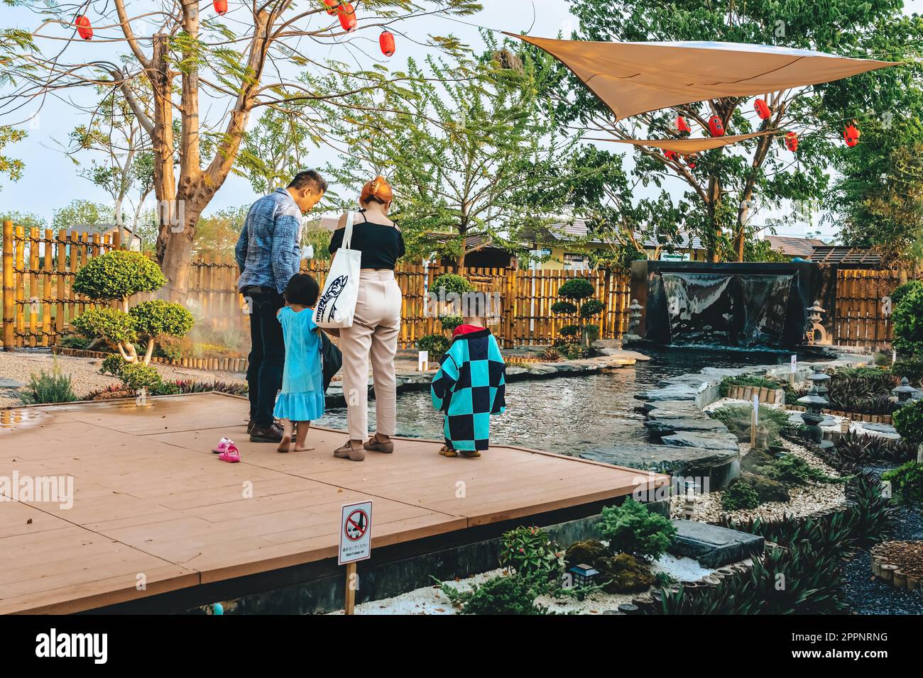 KANCHANABURI -THAÏLANDE, 30 MARS 2023 : touristes non identifiés viennent visiter et nourrir koi ou carpe fantaisie dans un petit étang avec beau jardin décoré Banque D'Images