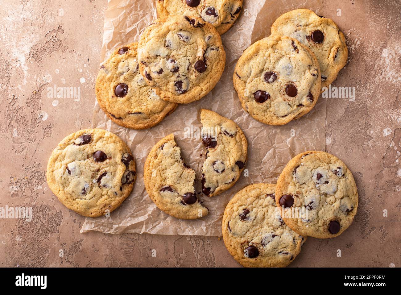 Biscuits aux pépites de chocolat au sel feuilleté sur papier parchemin, biscuits maison fraîchement cuits Banque D'Images