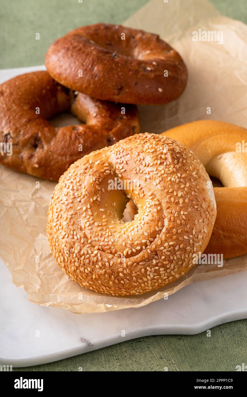 Bagels maison fraîchement cuits sur un papier parchemin prêt à manger, raisins secs de cannelle, sésame et bagel simple Banque D'Images