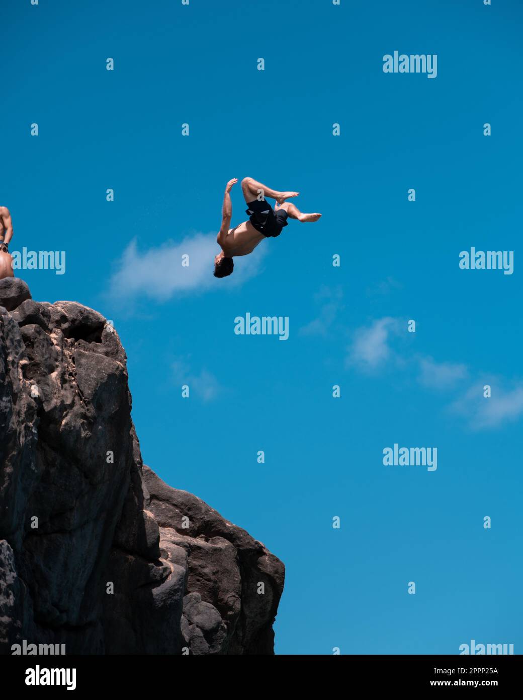 Homme plongée sur la falaise et flipping à Waimea Bay à Oahu, Hawaï en été. Banque D'Images