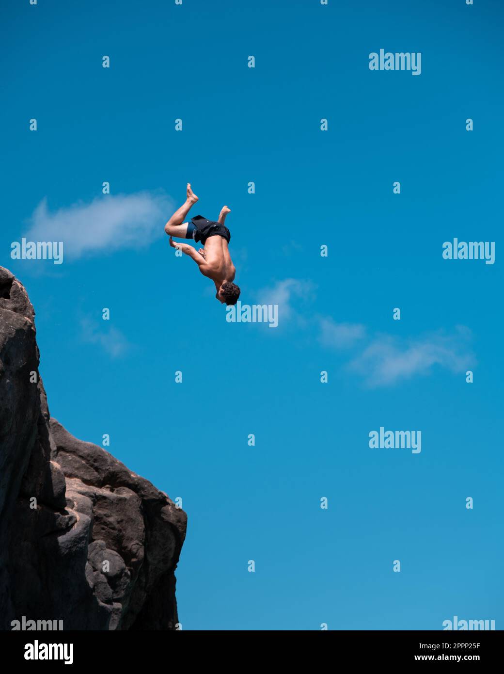 Homme plongée sur la falaise et flipping à Waimea Bay à Oahu, Hawaï en été. Banque D'Images