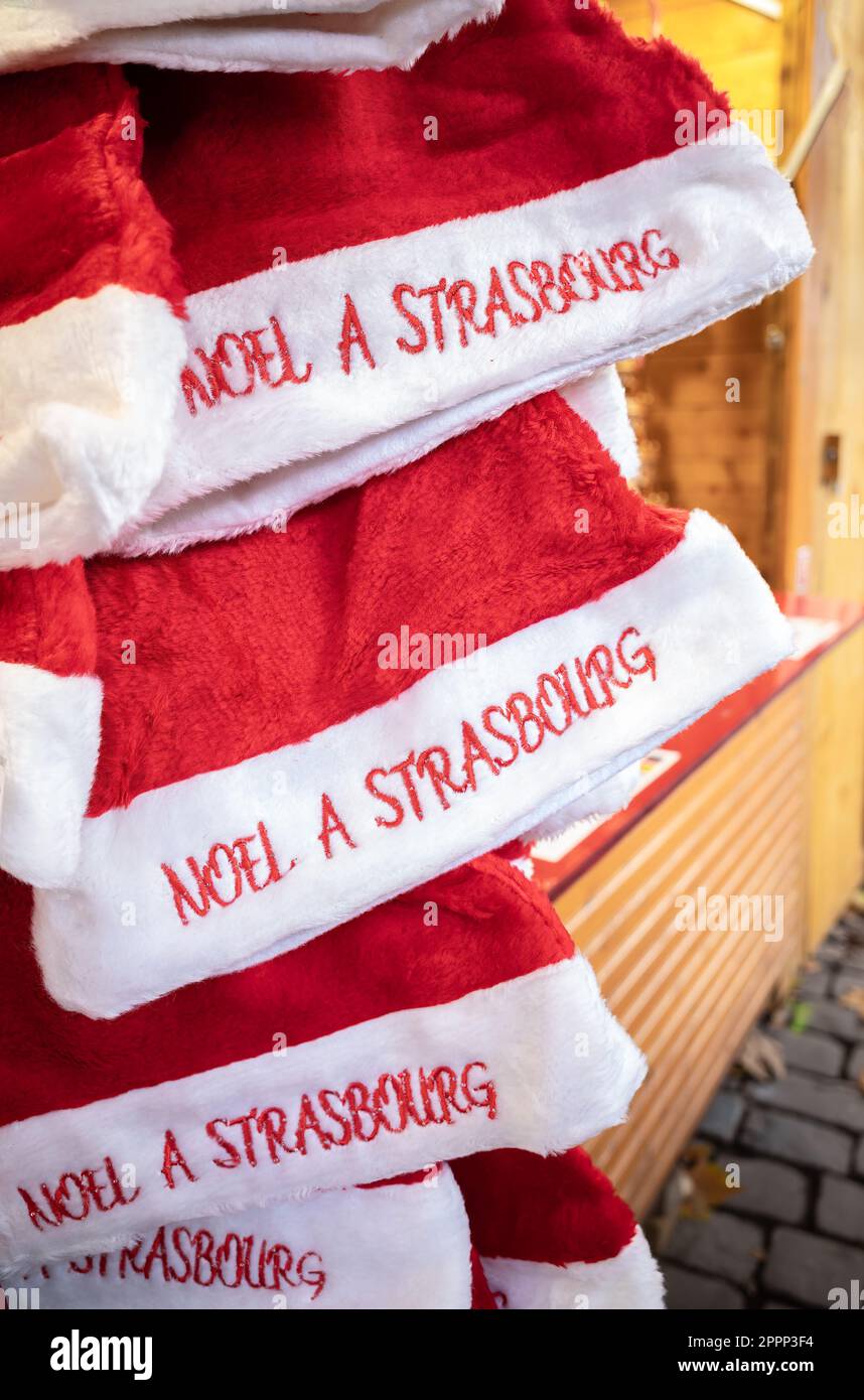 Chapeaux de Noël rouges et blancs sur un marché de Noël avec inscription française en traduction anglaise : Noël à Strasbourg Banque D'Images