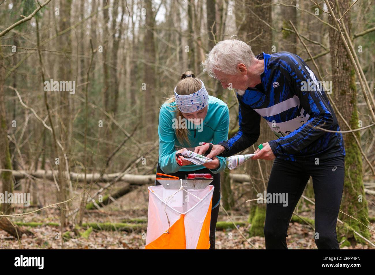 Grodno, Bélarus - 26 mars 2023: Homme caucasien âgé fort portant des vêtements de sport aide à l'athlète adolescente fille pendant l'exercice en plein air orienteerin Banque D'Images