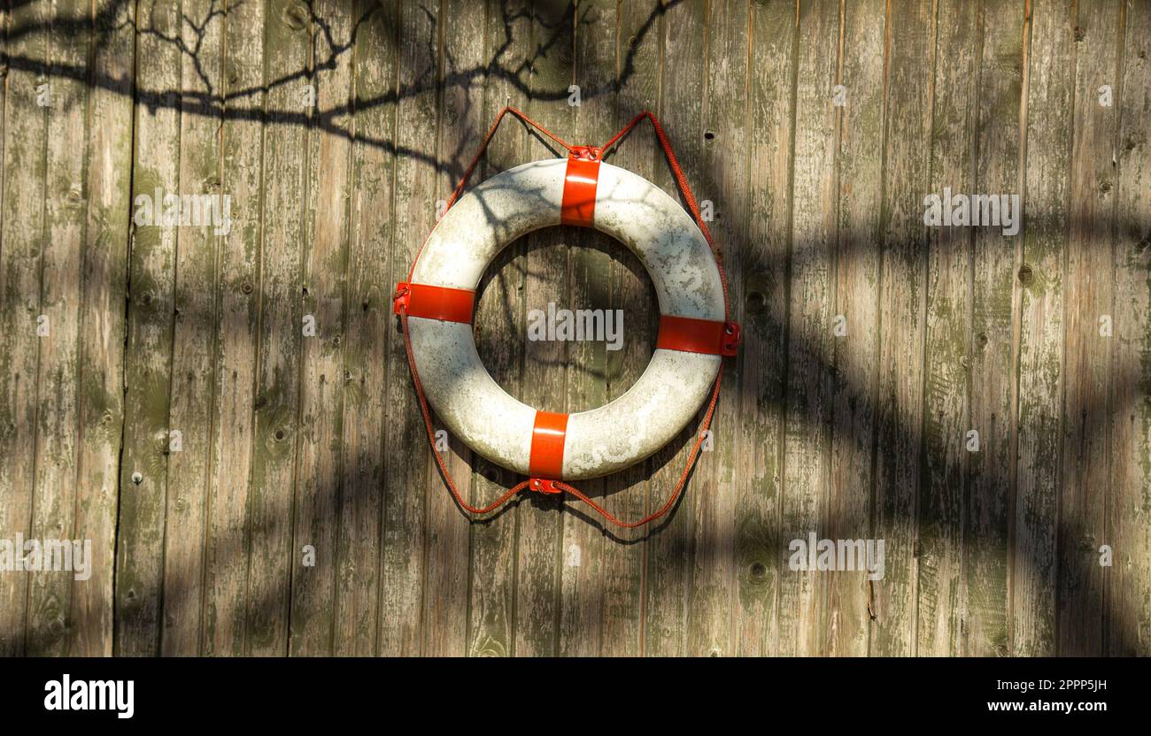 Bouée de sauvetage blanche sur un mur en bois près de l'eau. Équipement de sauvetage Banque D'Images