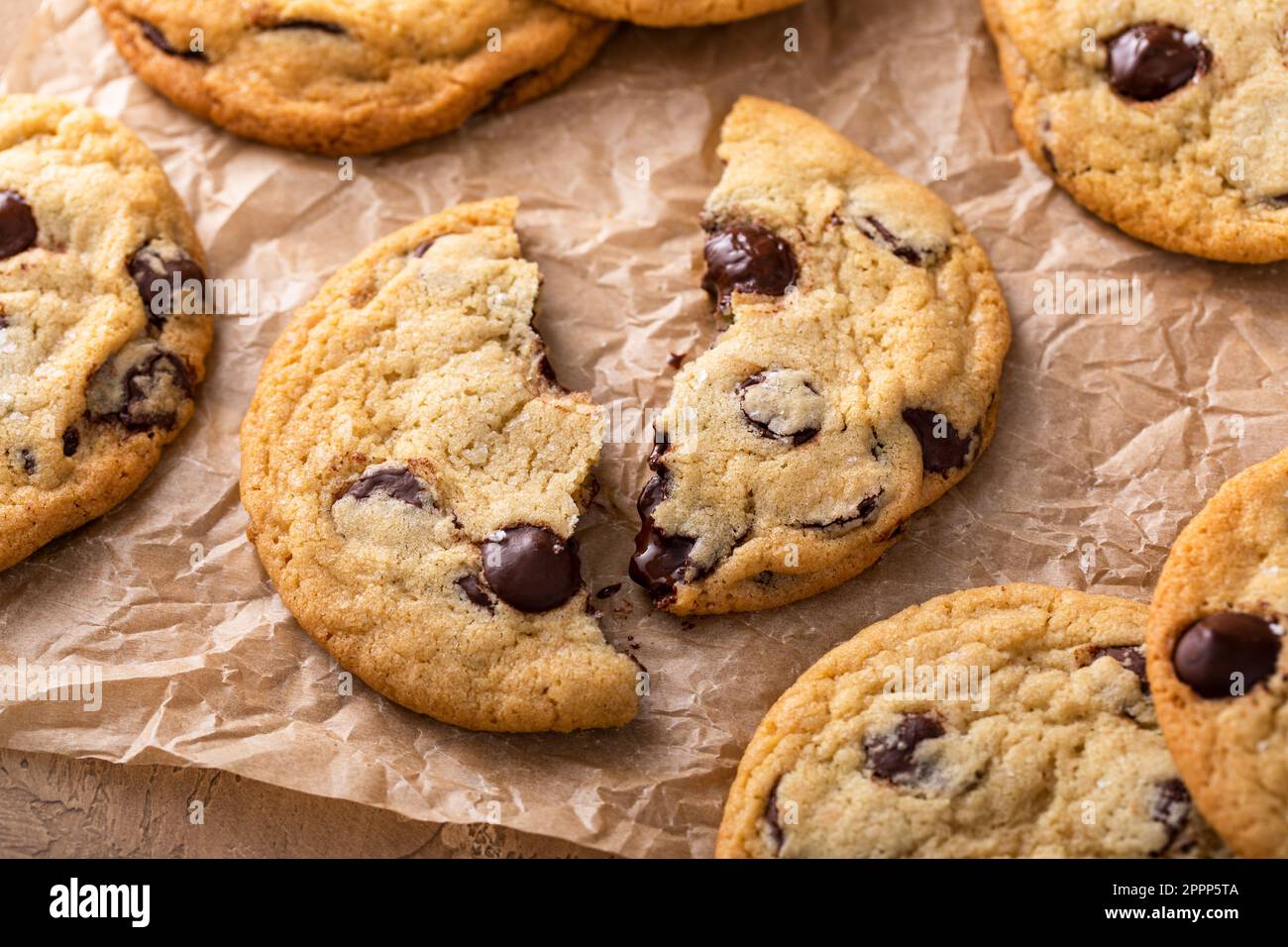 Biscuits aux pépites de chocolat au sel feuilleté sur papier parchemin, biscuits maison fraîchement cuits Banque D'Images