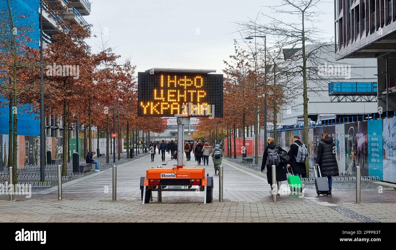 Panneau électronique 'Info centre Ukraine': Message pour les Ukrainiens en langue ukrainienne près de la gare. Des gens avec des valises. Banque D'Images