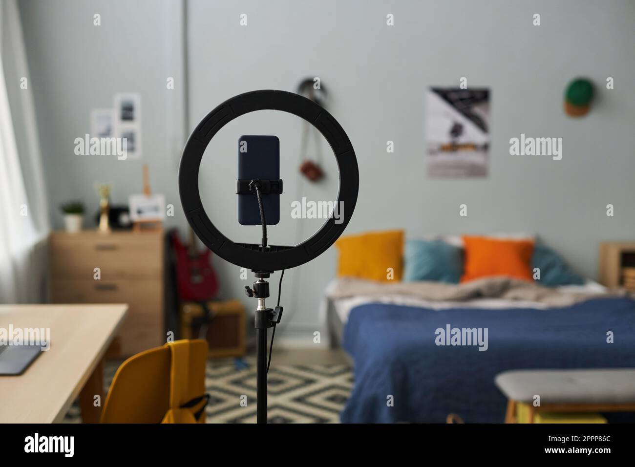Concentrez-vous sur un cadre rond avec un smartphone au centre de la chambre avec un lit double avec plusieurs coussins, une chaise avec sac à dos et un bureau Banque D'Images