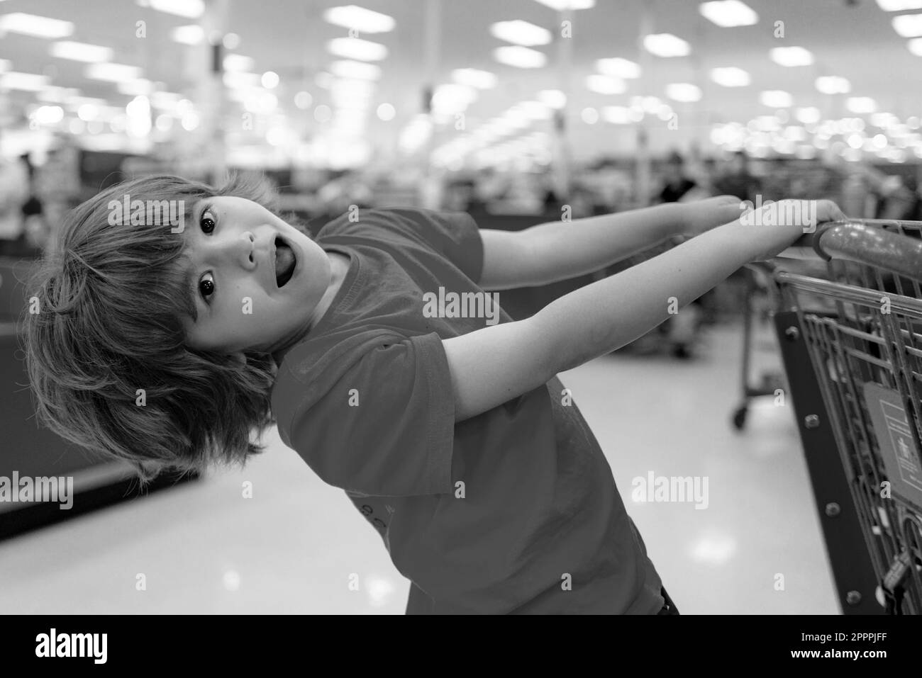 Un garçon fait du shopping dans un supermarché. Drôle d'enfant avec chariot de shopping avec dans l'épicerie. Banque D'Images
