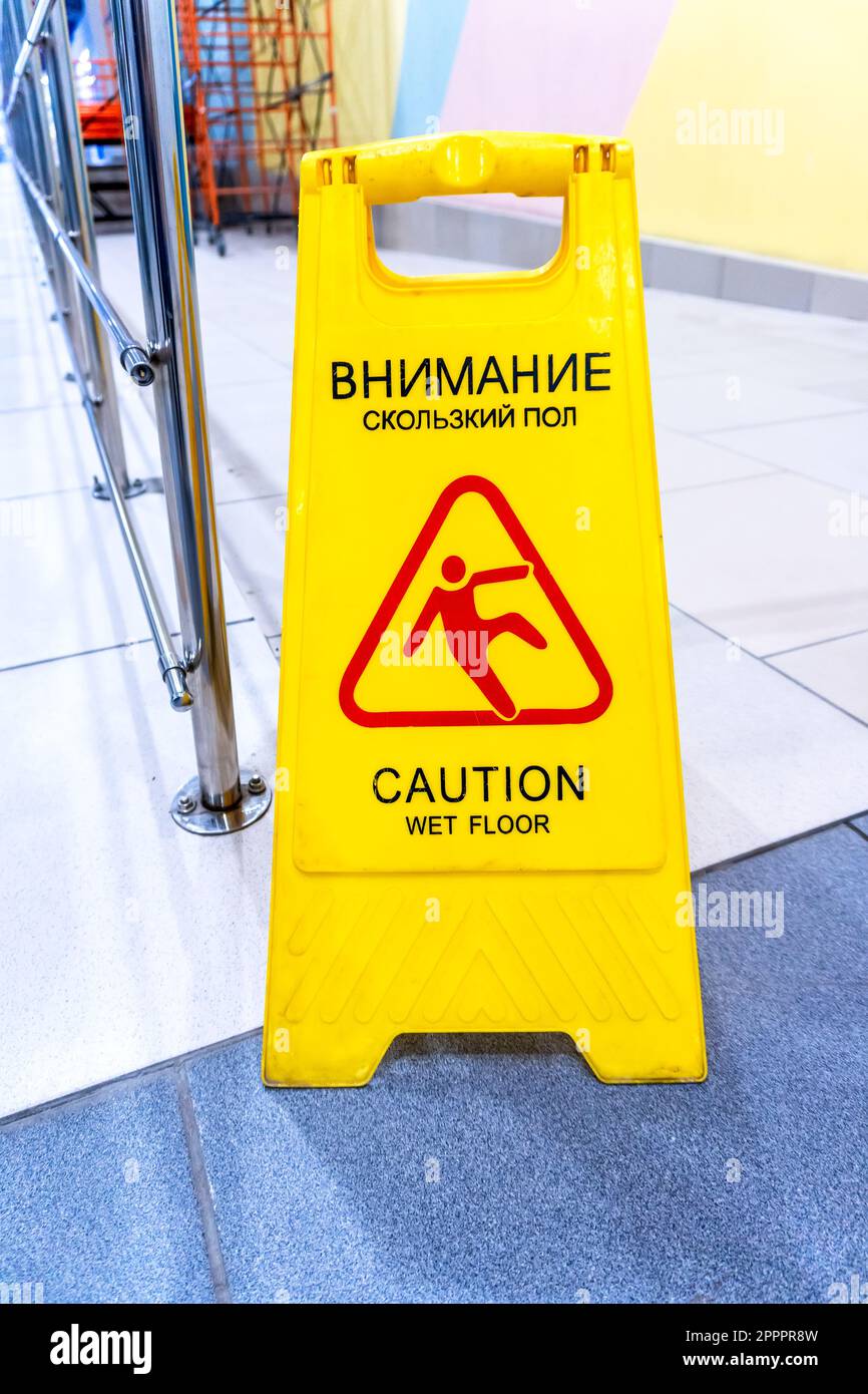 Attention panneau d'avertissement jaune sur sol mouillé sur un plancher en carreaux dans un magasin secondaire Banque D'Images
