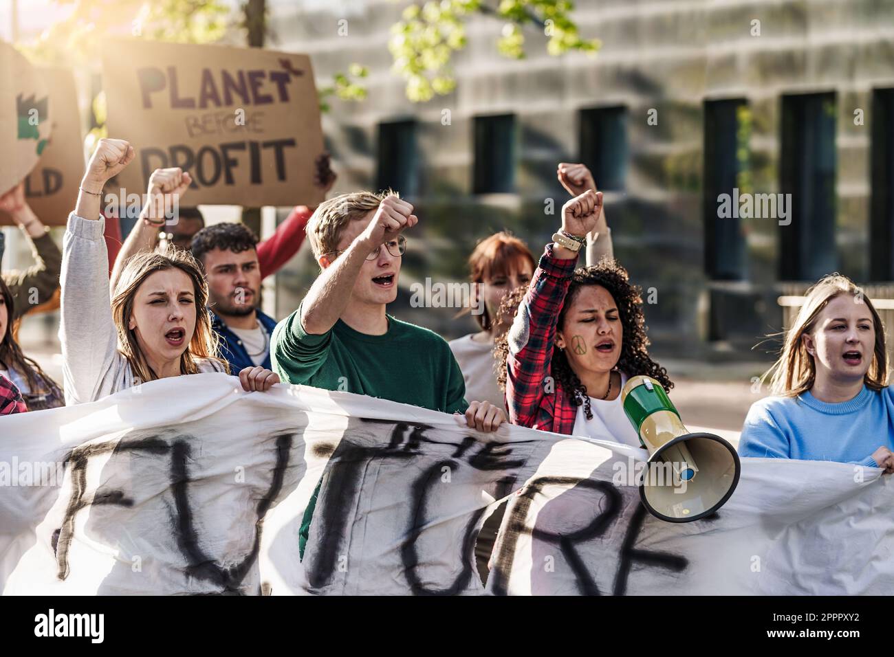 Groupe de jeunes de vingt ans marchant avec des poings levés, des mégaphones, des visages peints et des signes lisant « planète avant le profit » et « avenir ». Banque D'Images