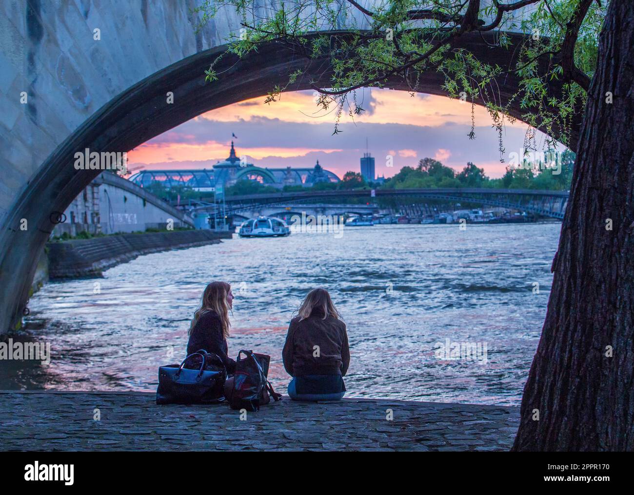 05-15-2016 Paris, France. 2 filles (jeune femme) assises à côté de la Seine et parlant de la vie au crépuscule . En arrière-plan - Grand Palais (Big Pa Banque D'Images