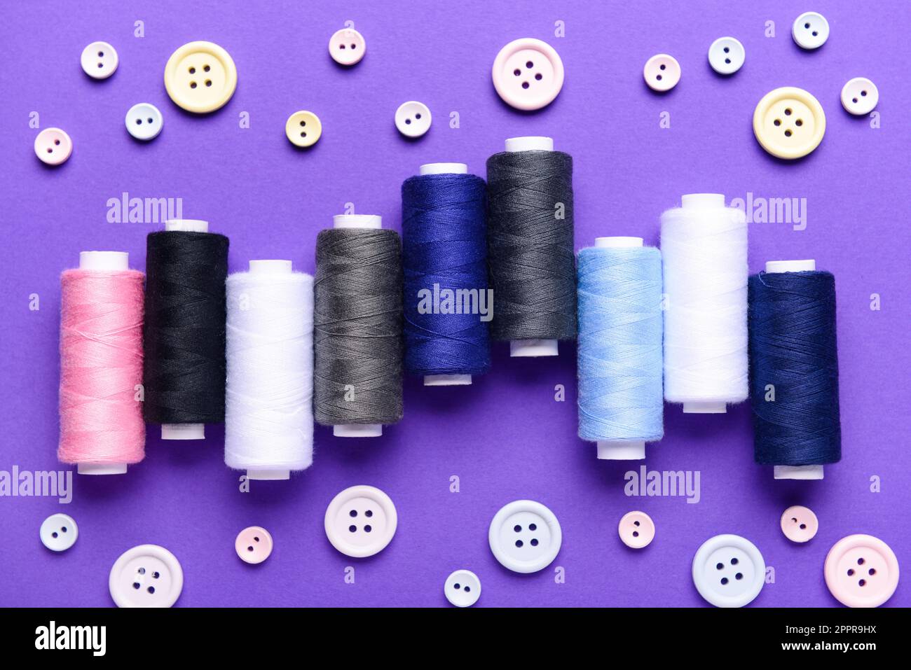 Composition avec différentes bobines de filetage et boutons sur fond de couleur Banque D'Images