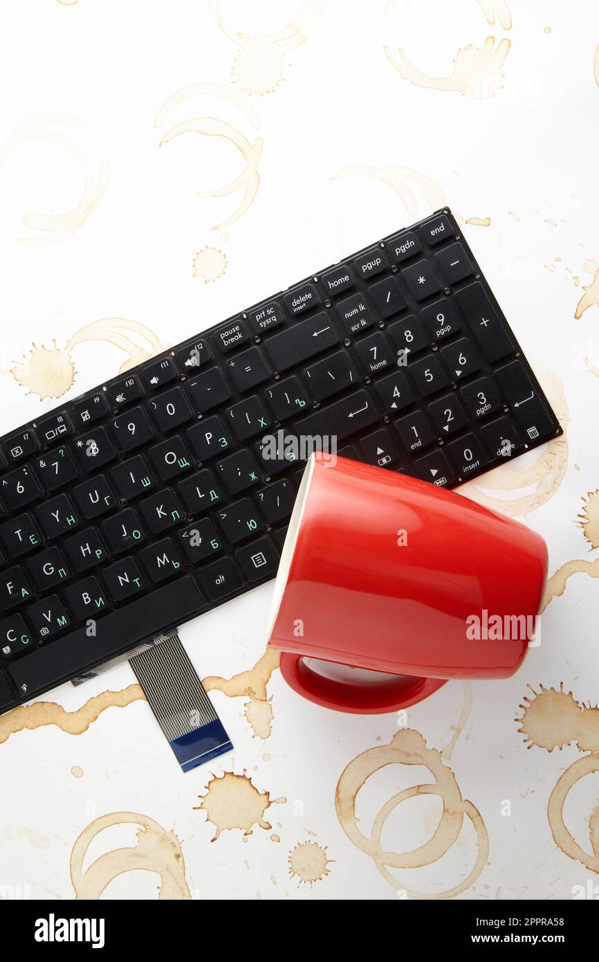 Une tasse de café rouge est brocartée sur un clavier d'ordinateur Banque D'Images Une tasse de café rouge est brocartée sur un clavier d'ordinateur Banque D'Images