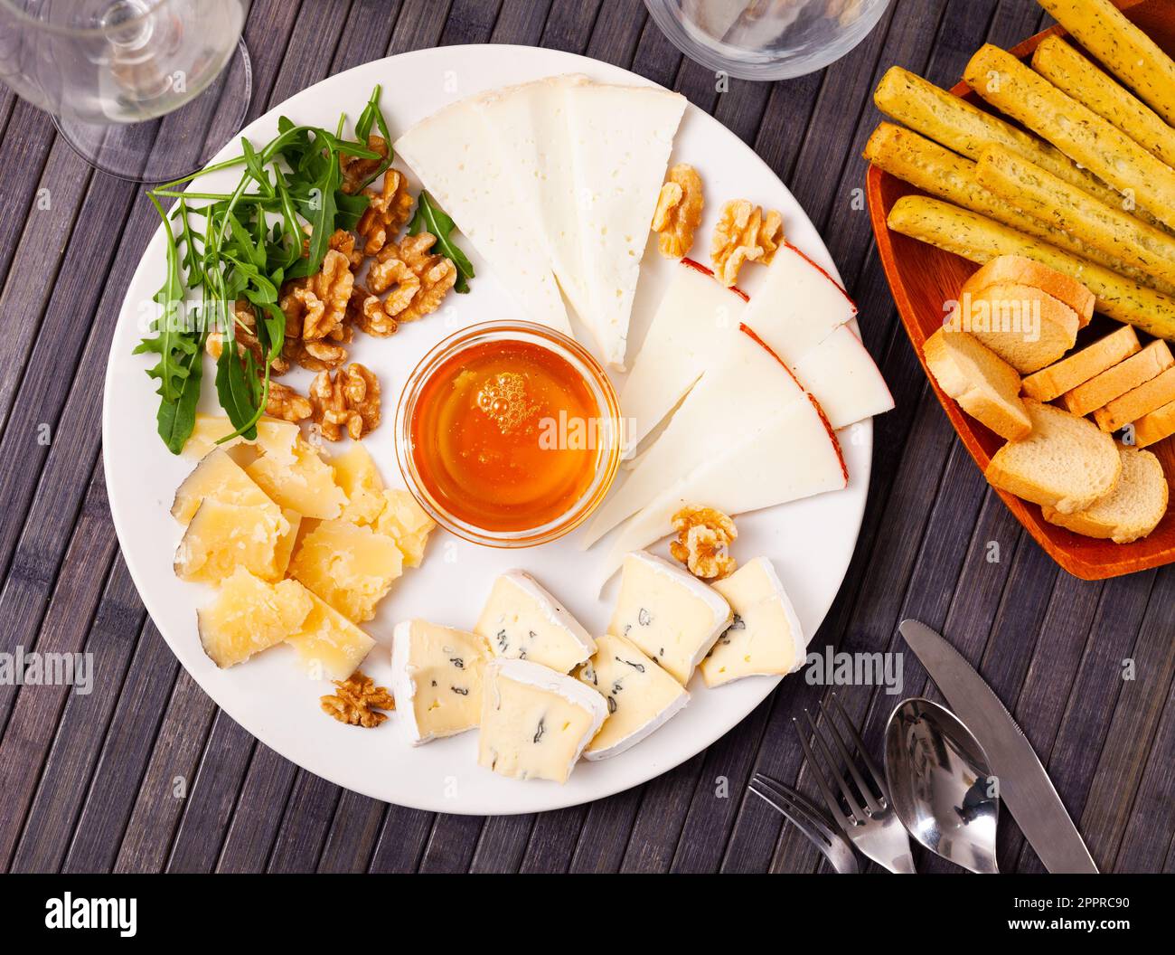 Différents types de fromage tranchés et servis sur une assiette avec un bol de miel, des noix Banque D'Images
