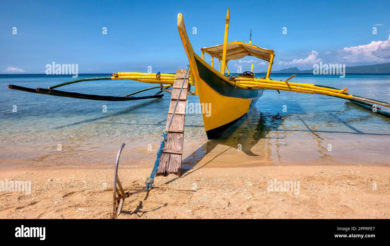 Vue rapprochée de l'arc d'un bateau à stabilisateur en bois aux Philippines, connu localement sous le nom de banca, ancré dans des eaux turquoise peu profondes. Banque D'Images