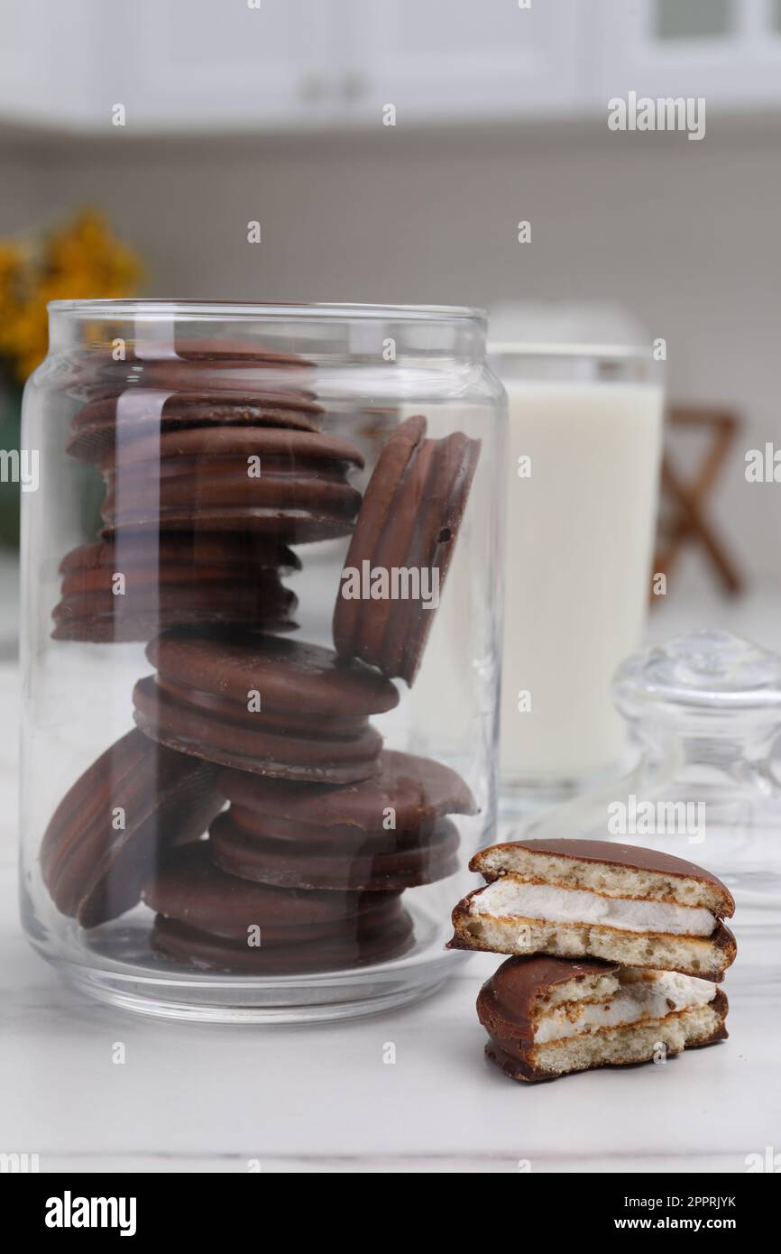 Bol avec de délicieuses tartes au chocolat et un verre de lait sur une table blanche dans la cuisine Banque D'Images