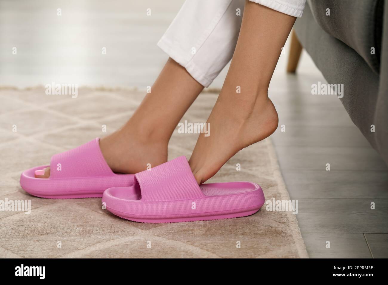 Femme mettant des chaussons roses à l'intérieur, gros plan Banque D'Images
