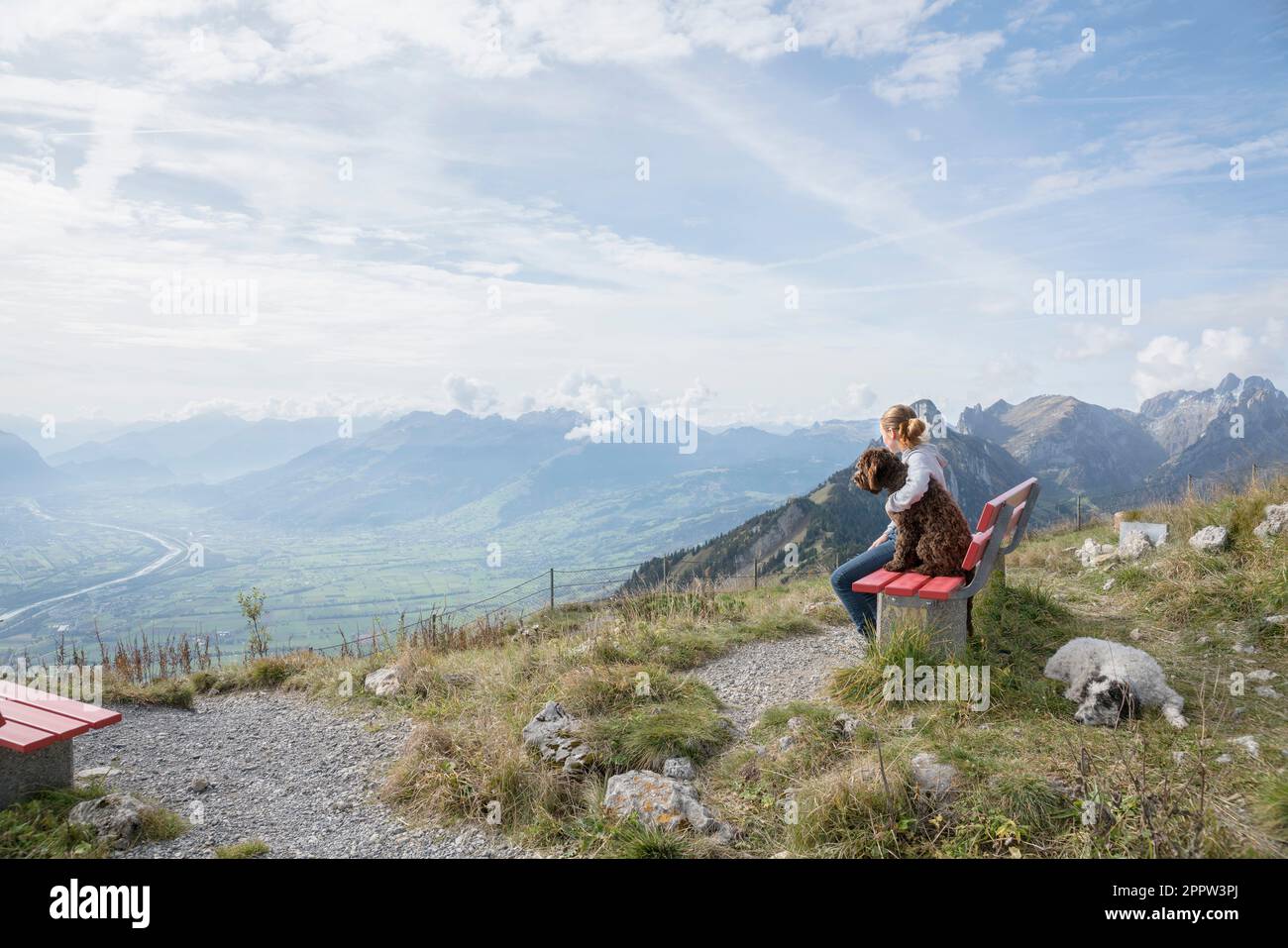 Jeune fille avec des chiens assis sur le banc et bénéficiant d'une vue panoramique et majestueuse sur la chaîne de montagnes, Suisse Banque D'Images