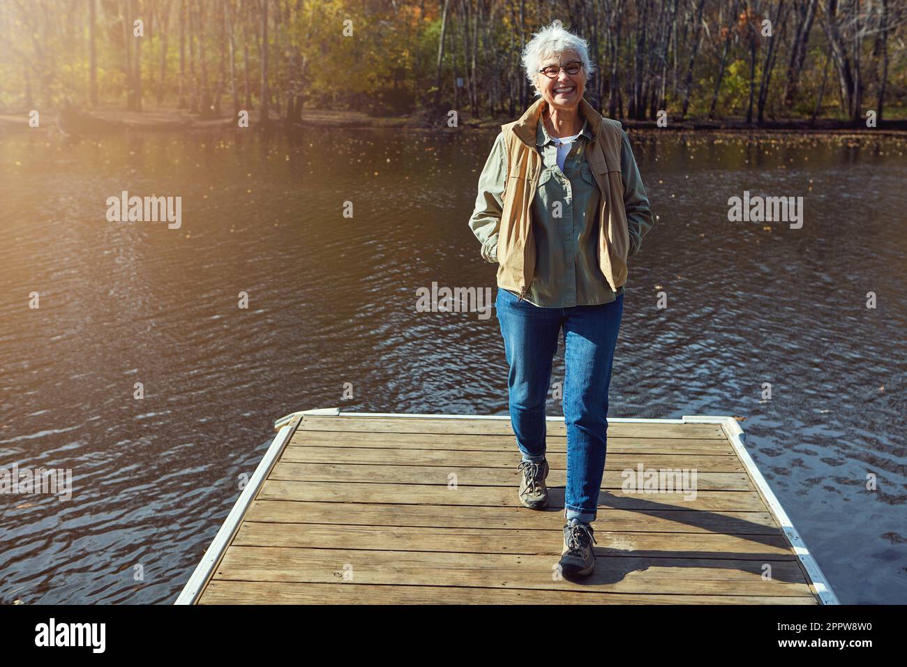 C'est exactement ce à quoi je voulais prendre ma retraite. une femme âgée se rendant pour une promenade sur une jetée à côté d'un lac. Banque D'Images