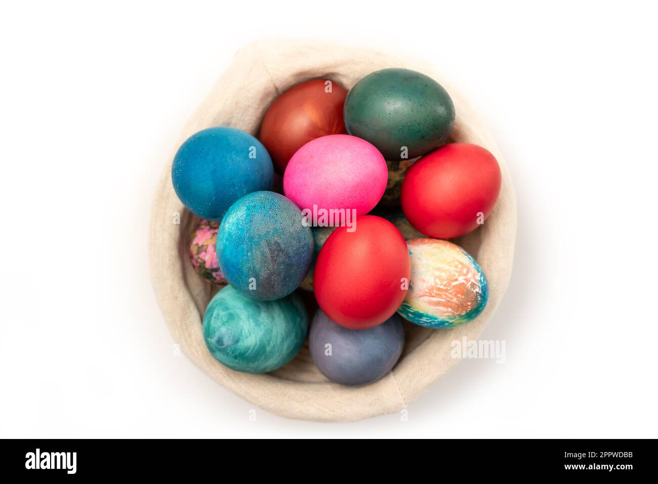 Œufs de Pâques multicolores dans le panier tissé isolé sur fond blanc avec passe-cheveux Banque D'Images