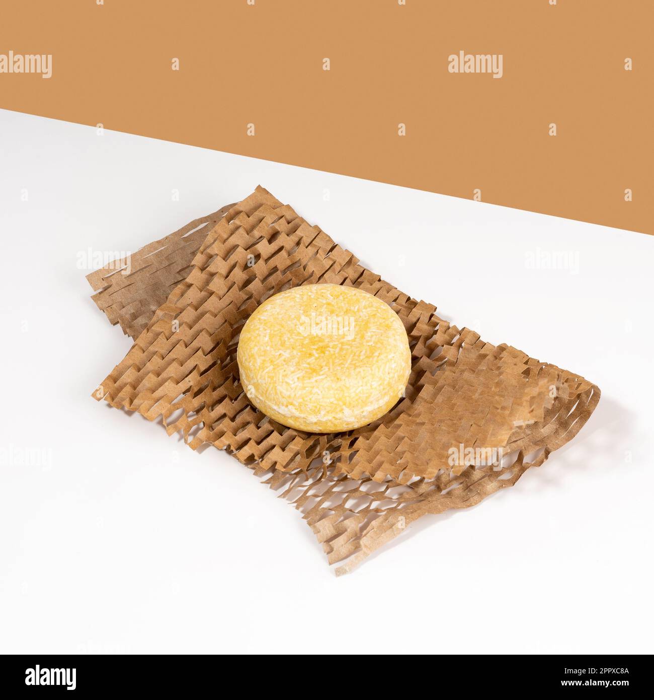 Barre de shampooing solide durable reposant sur un papier nid d'abeilles sur un fond blanc brun. Soin des cheveux écologique. Sans plastique, aucun gaspillage Banque D'Images