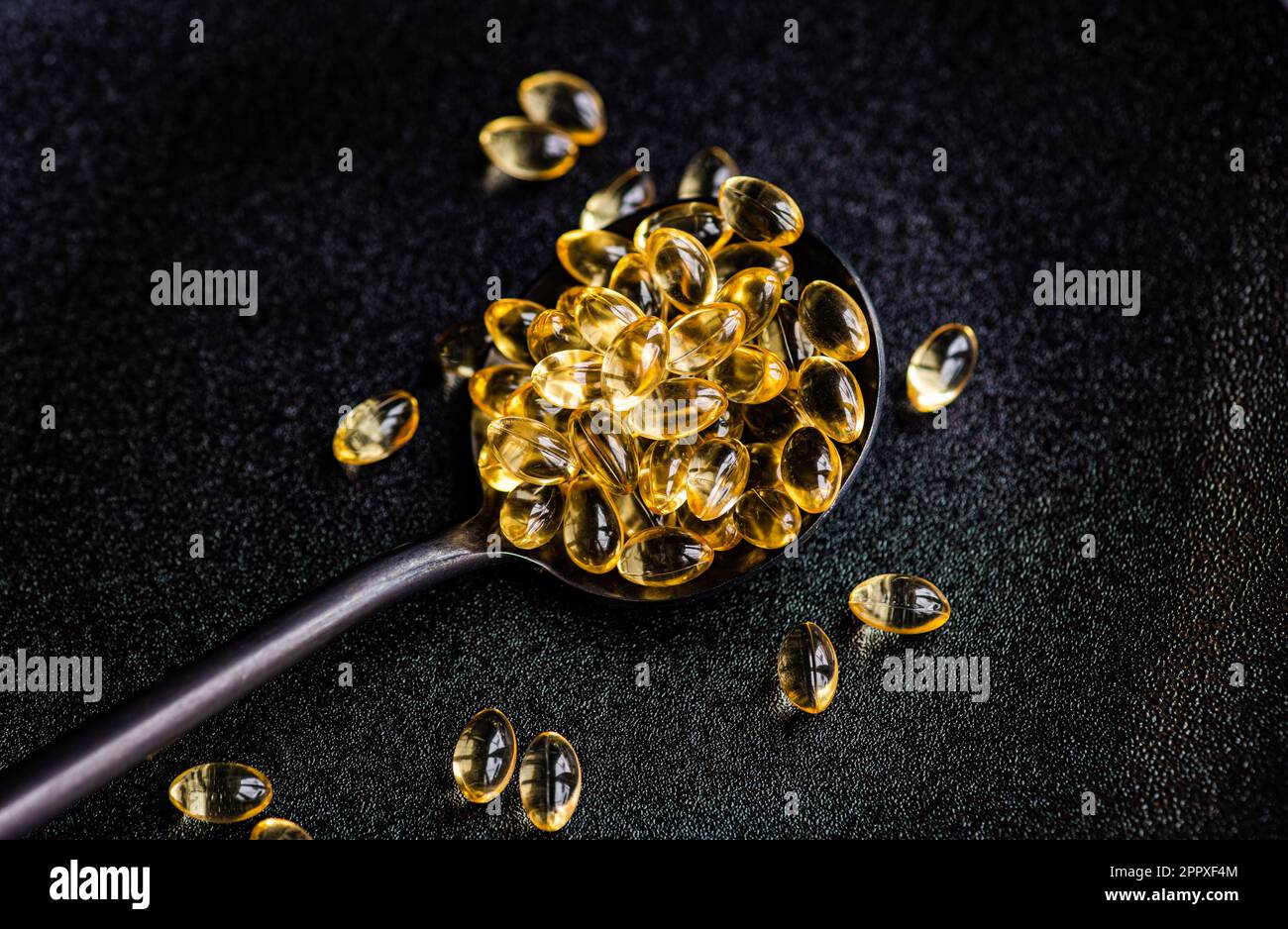 Concept de vie saine avec des médicaments de vitamine huileux dans la cuillère noire sur l'assiette de manque Banque D'Images