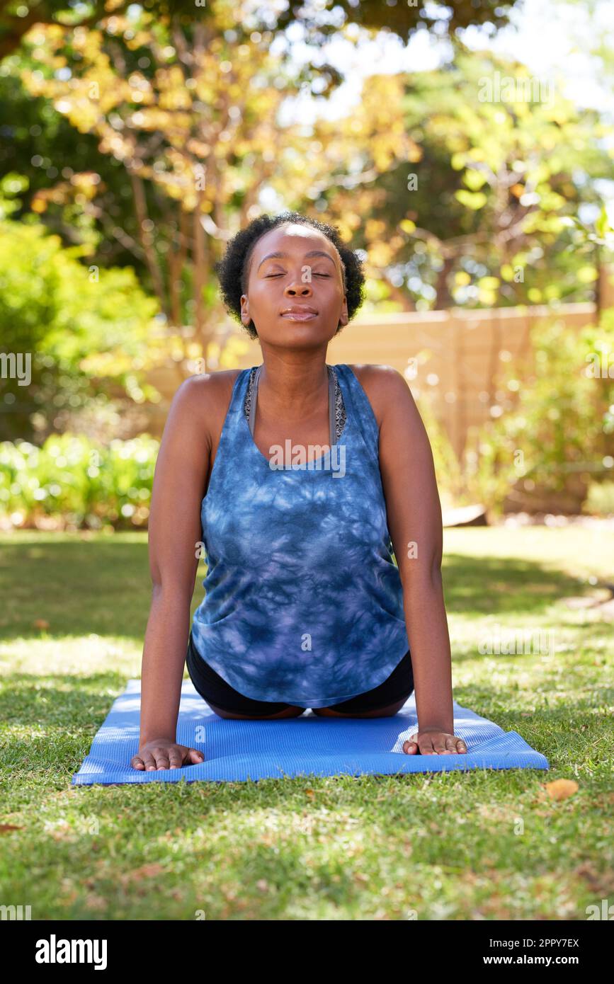 Belle jeune Black Woman fait face vers le haut chien yoga pose à l'extérieur, arbres Banque D'Images