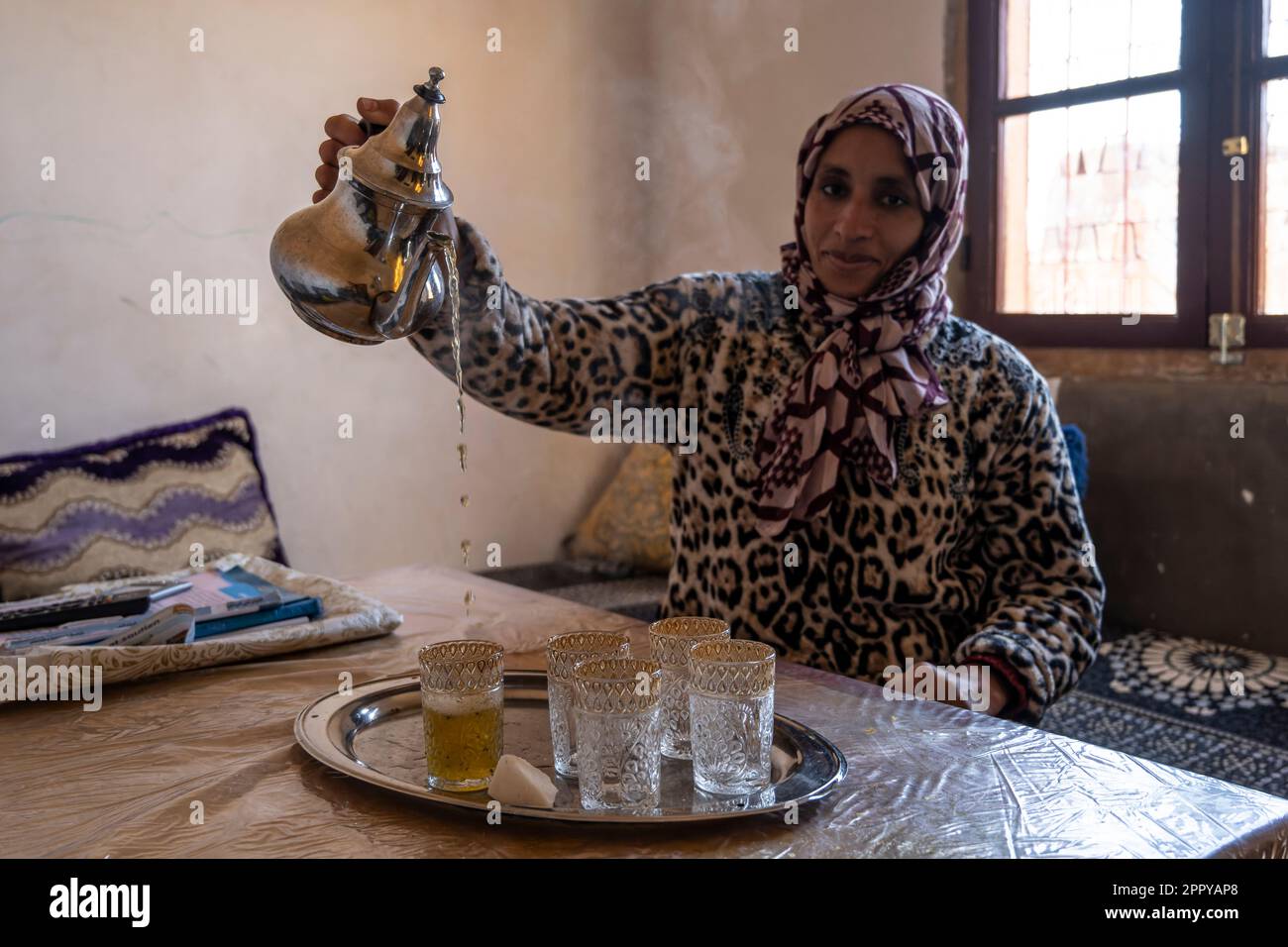 La femme berbère sert le thé de façon traditionnelle. Banque D'Images