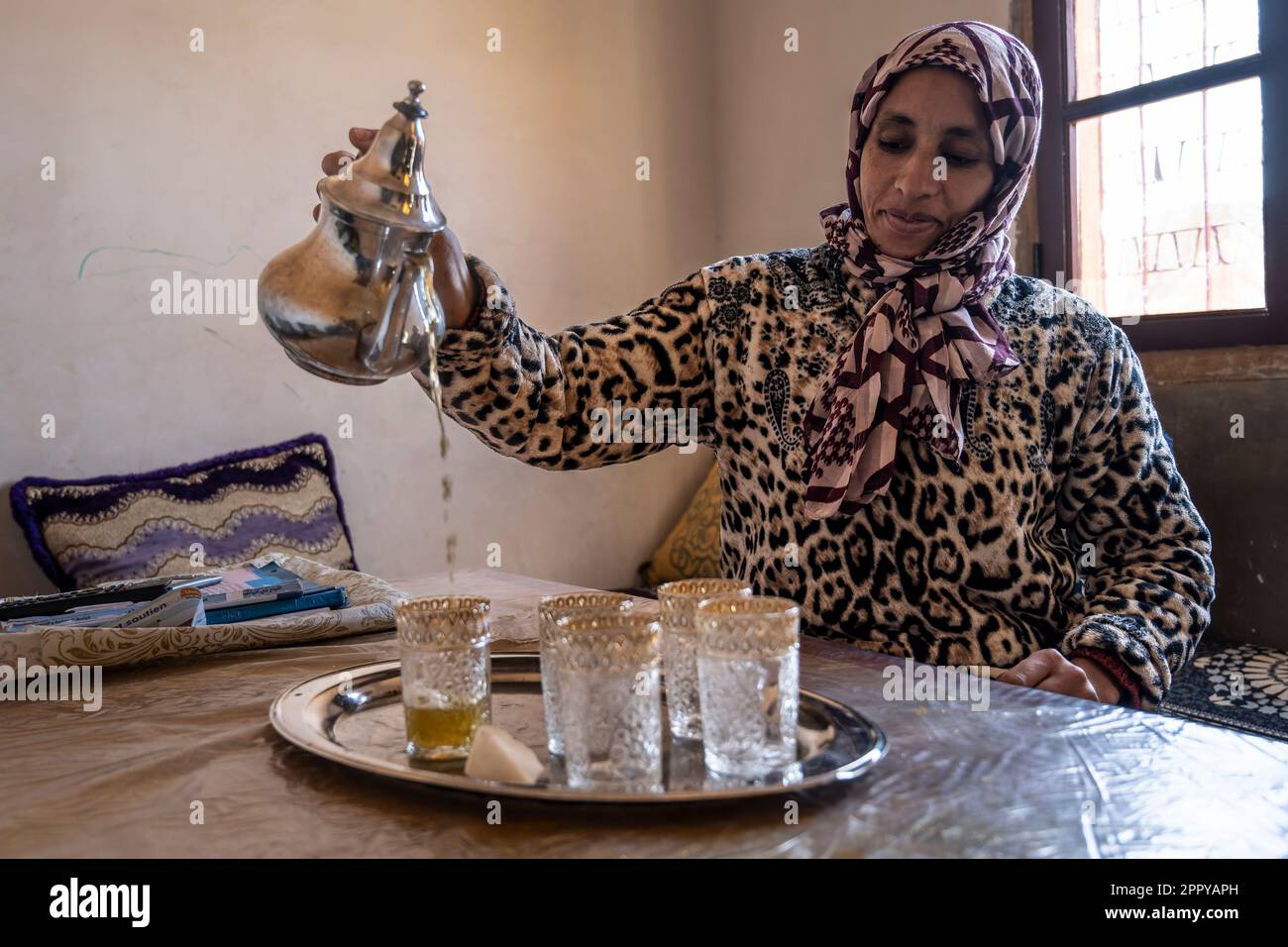 La femme berbère sert le thé de façon traditionnelle. Banque D'Images