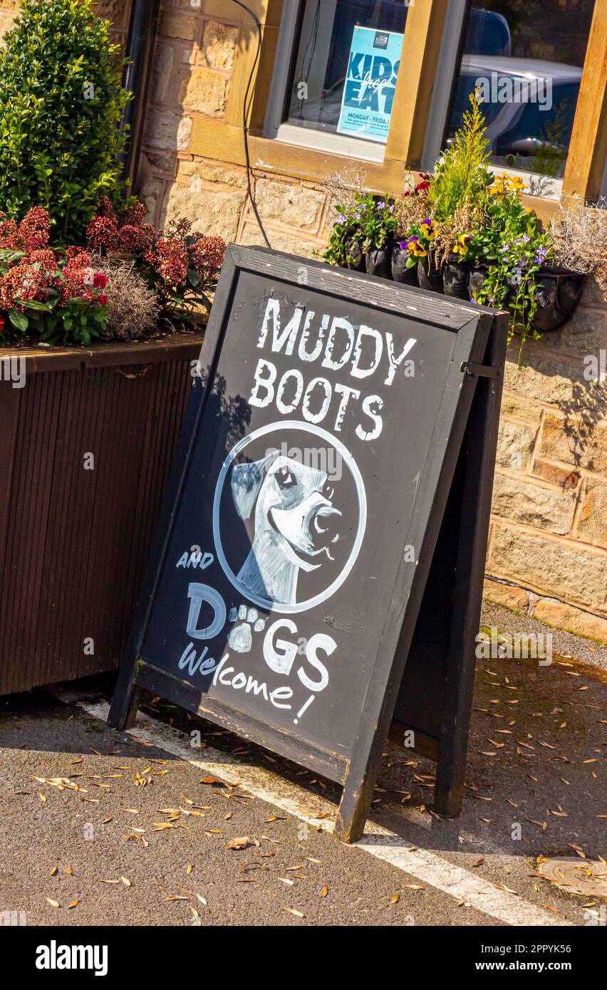 Bottes et chiens boueux affiche de bienvenue sur un tableau à l'extérieur d'un pub britannique accueillant les randonneurs. Banque D'Images