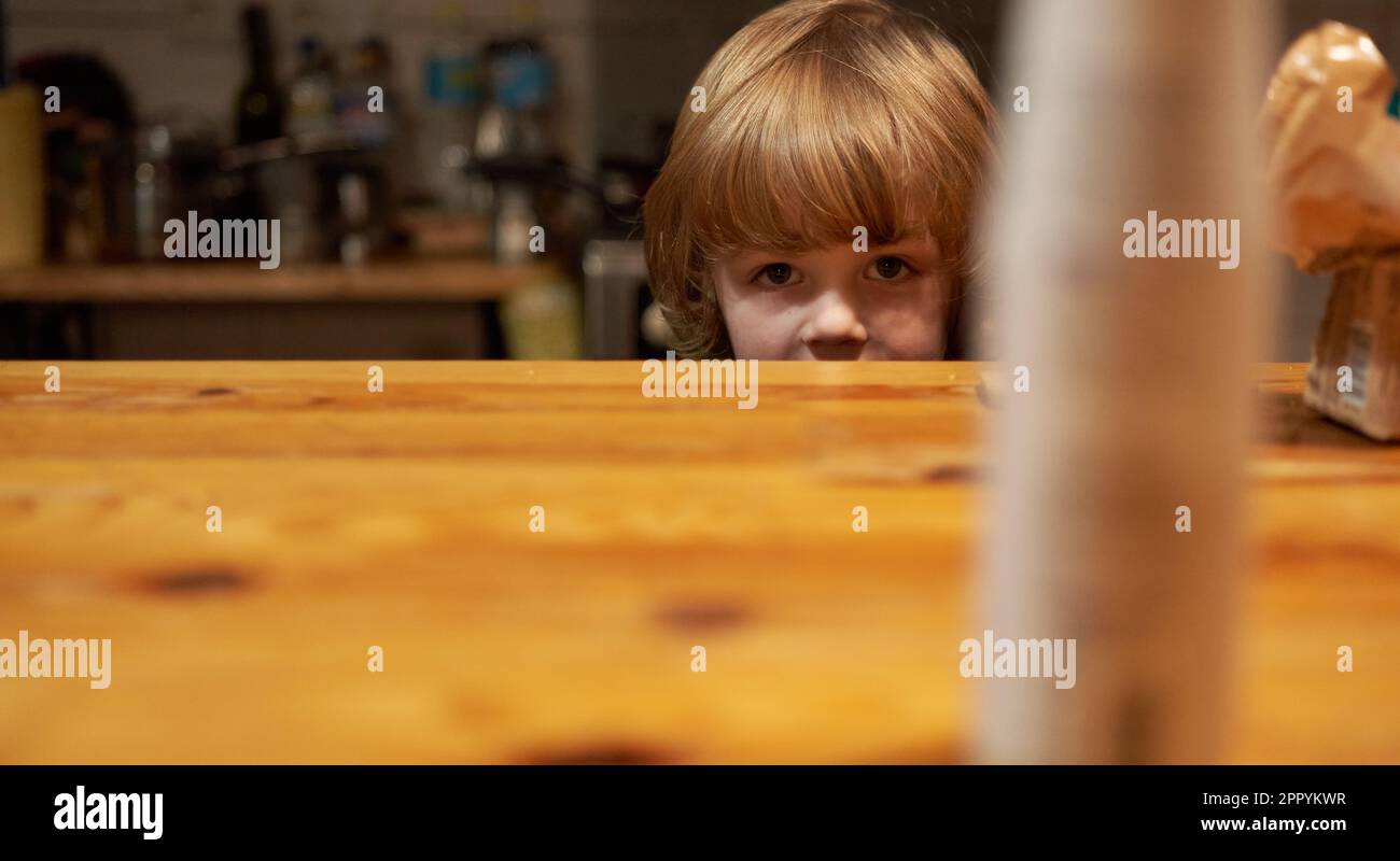 Portrait d'un enfant aux cheveux bouclés assis à une table Banque D'Images