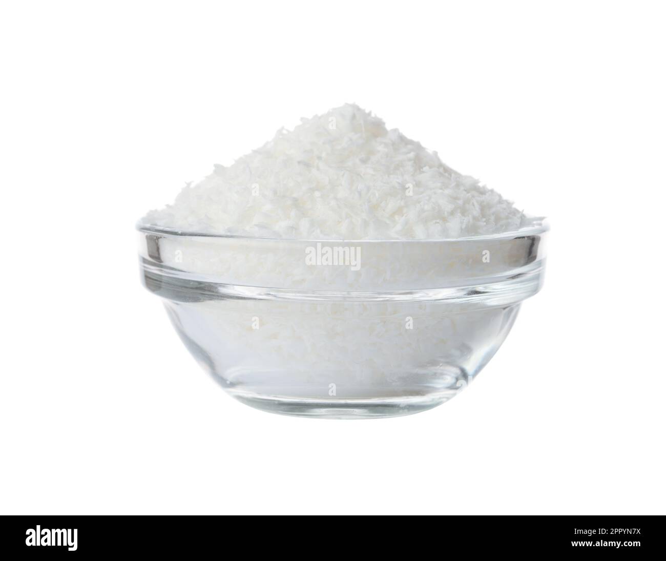Flocons de noix de coco dans un bol en verre isolé sur blanc. Banque D'Images