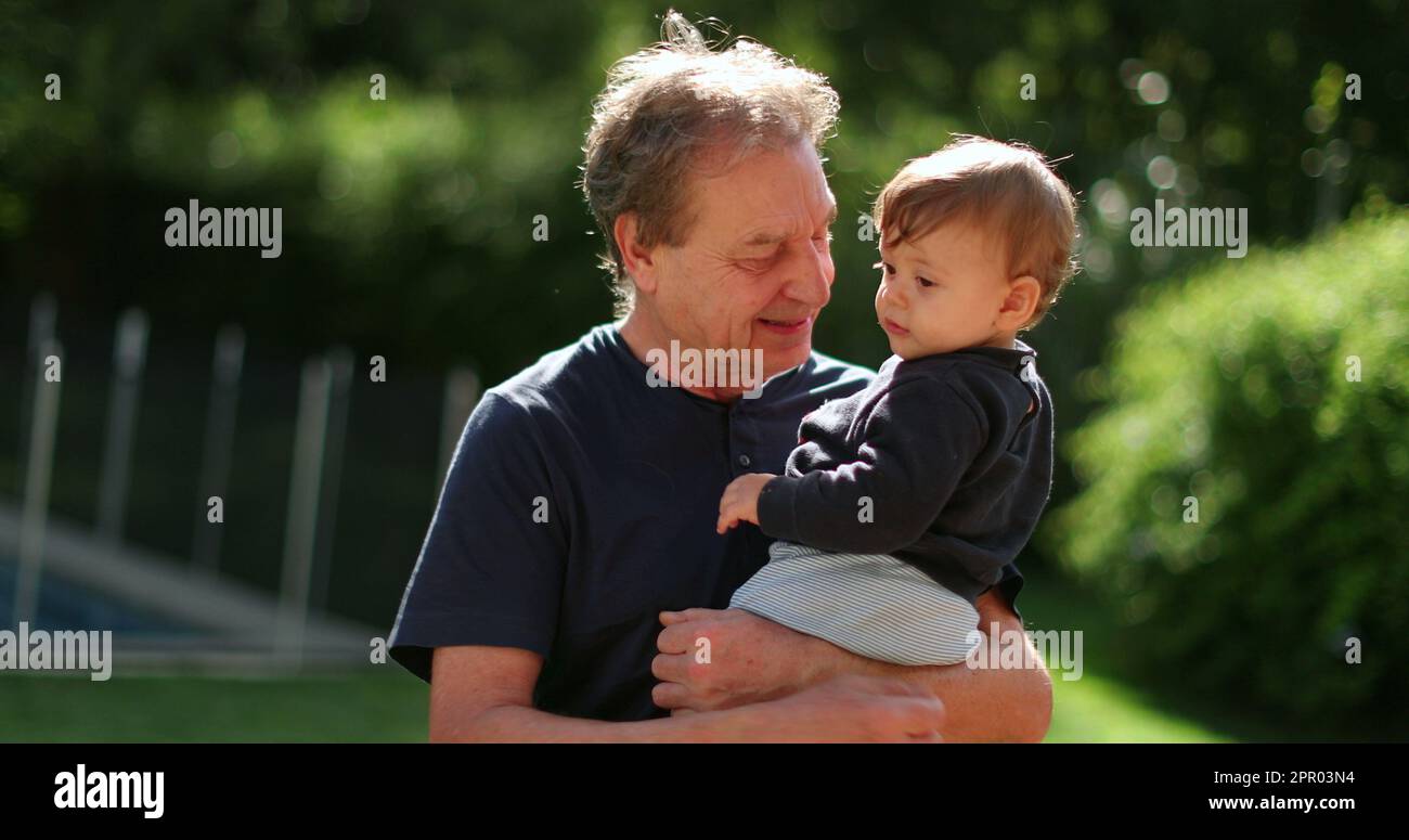 Grand-père tenant le bébé dans les bras à l'extérieur dans l'arrière-cour. Liaison grand-parent avec grand-enfant Banque D'Images