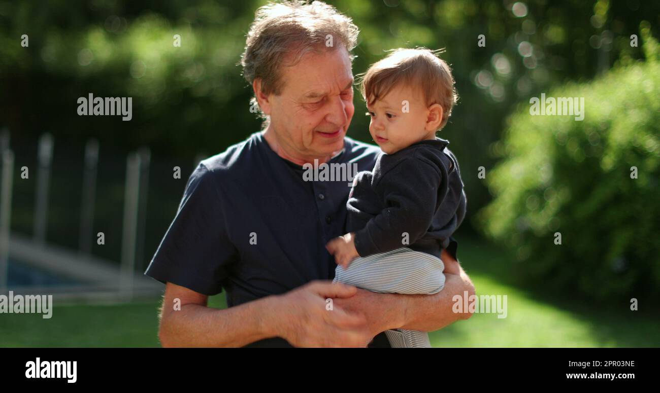 Grand-père tenant le bébé dans les bras à l'extérieur dans l'arrière-cour. Liaison grand-parent avec grand-enfant Banque D'Images
