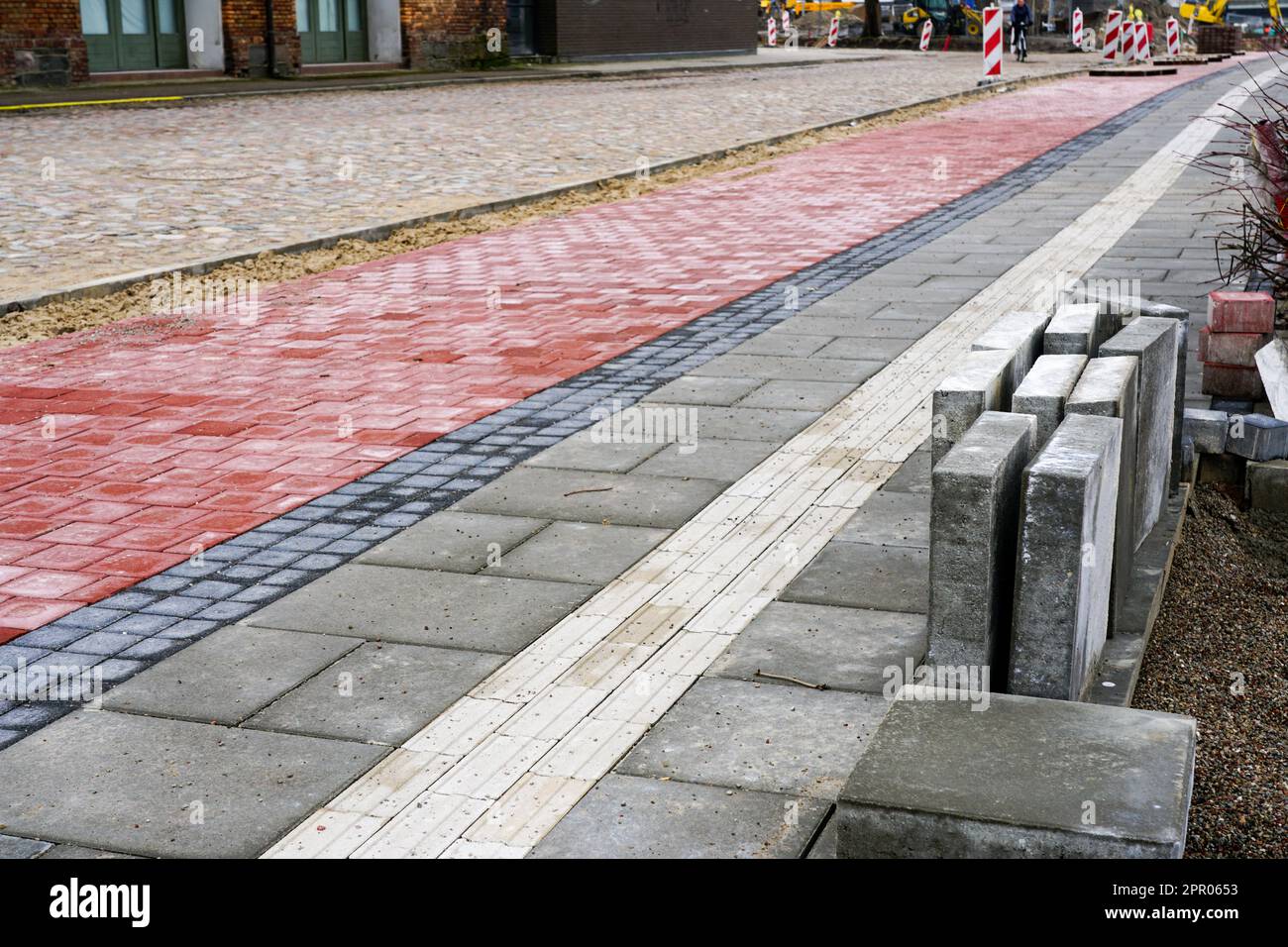 Pose d'un nouveau trottoir avec une piste cyclable et des lignes directrices pour les malvoyants, pavés tactiles Banque D'Images