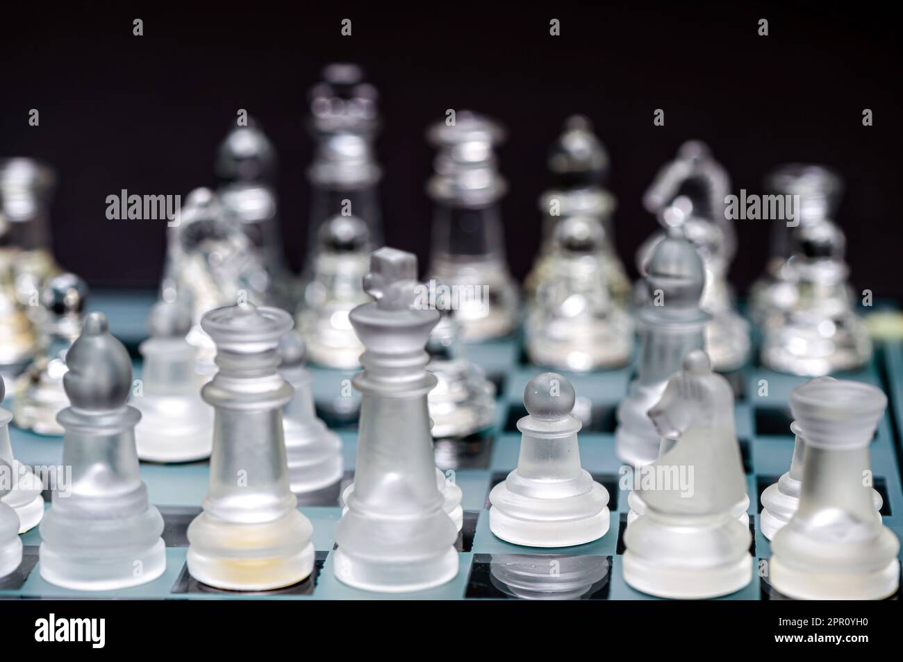 verre transparent, pièces d'échecs transparentes sur un damier, mise au point sélective, gros plan, isolé sur le noir Banque D'Images