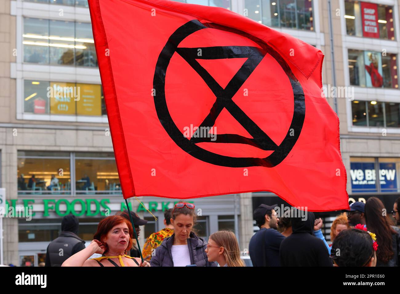 Une personne détient un drapeau rouge de la rébellion d'extinction dans le parc Union Square, à New York, au 21 avril 2023. Banque D'Images