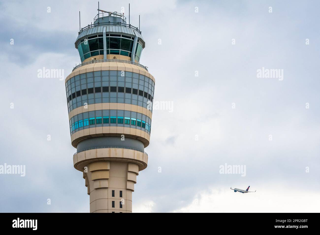 Le jet de Delta Air Lines monte dans les nuages au-delà de la tour de contrôle de la circulation aérienne à l'aéroport international Hartsfield-Jackson d'Atlanta, en Géorgie. Banque D'Images