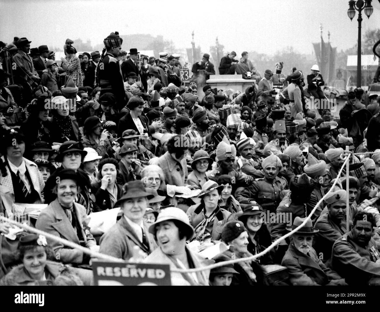 Photo du dossier datée du 12/05/37 de soldats de divers régiments d’infanterie et de cavalerie de l’Armée indienne assis avec des membres du public britannique au Queen Victoria Memorial, au Mall, dans l’après-midi du Couronnement du Roi George VI et de la Reine Elizabeth. Le grand-père du roi Charles III, George VI, a été couronné par sa consort, la reine Elizabeth, à la suite de la crise d'abdication qui a ébranlé la monarchie. Date de publication : mercredi 26 avril 2023. Banque D'Images