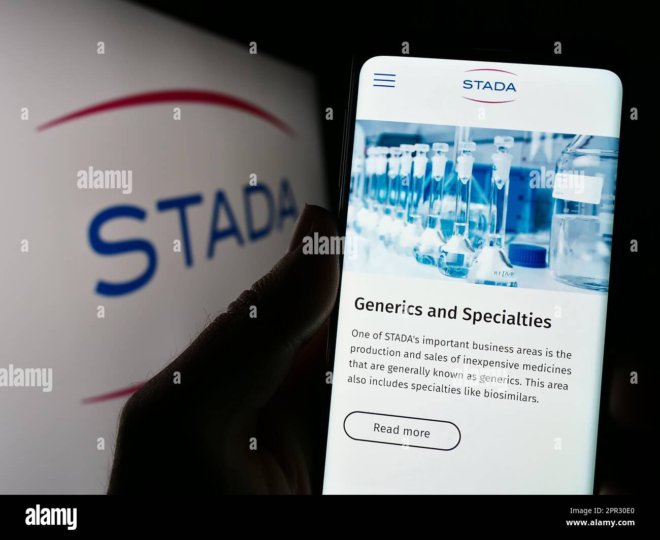 Personne tenant un téléphone portable avec le site de la société allemande Stada Arzneimittel AG à l'écran devant le logo. Concentrez-vous sur le centre de l'écran du téléphone. Banque D'Images