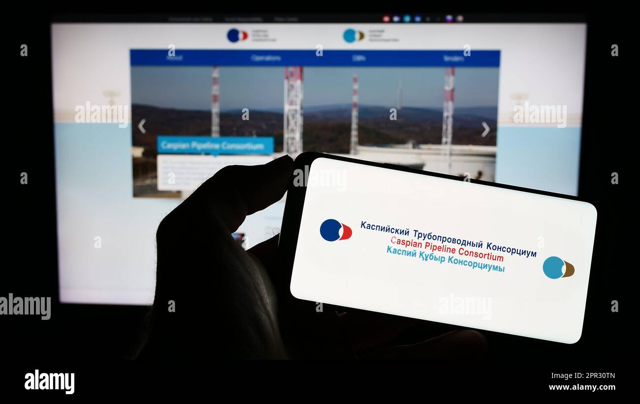 Personne tenant un téléphone portable avec le logo de Caspian Pipeline Consortium (CPC) à l'écran en face de la page Web des affaires. Mise au point sur l'affichage du téléphone. Banque D'Images