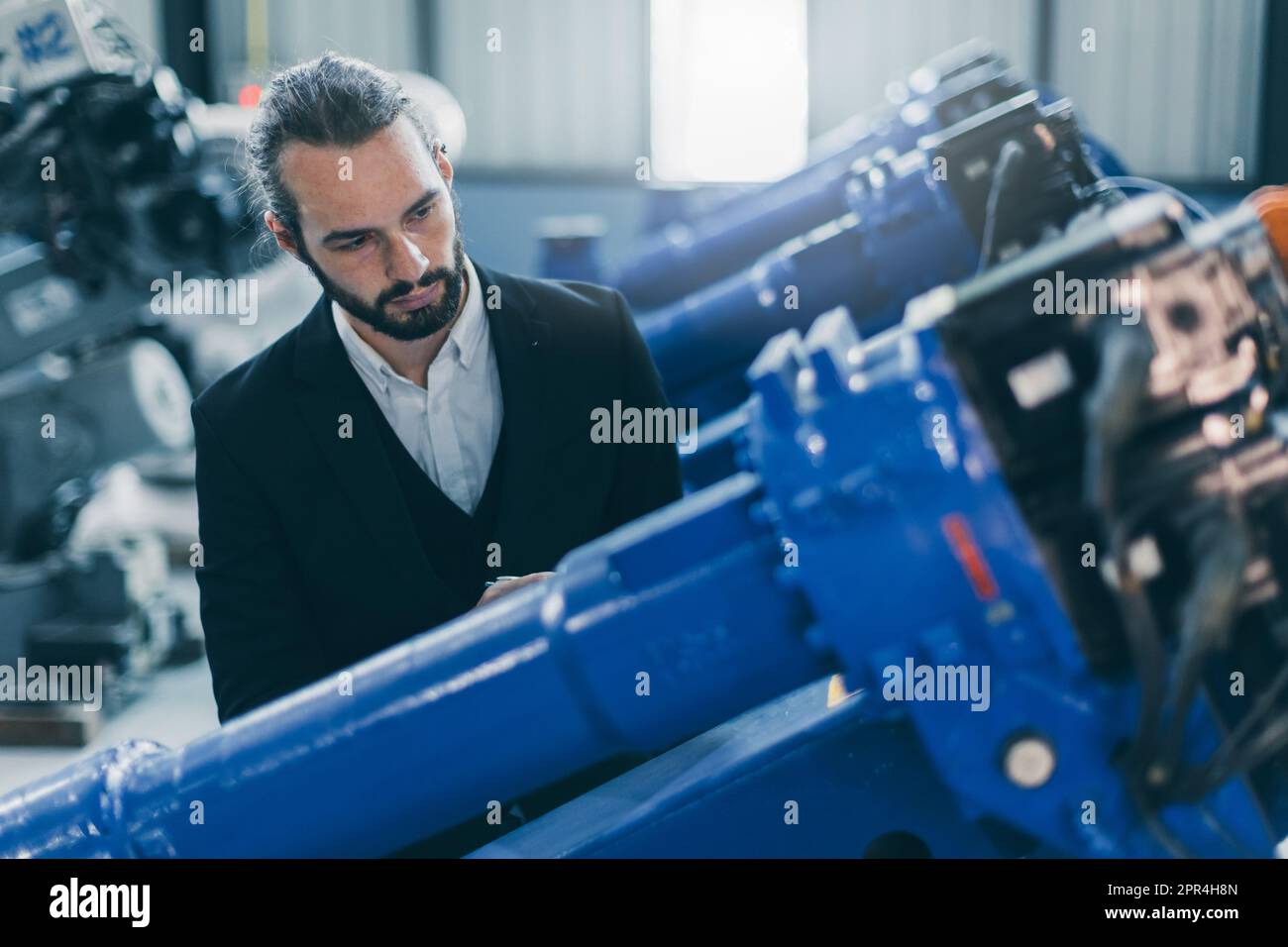Homme d'affaires en costume travaillant dans l'usine de fabrication de machines robot d'assemblage à la recherche de vérifier le stock de produits pour l'industrie des produits Banque D'Images