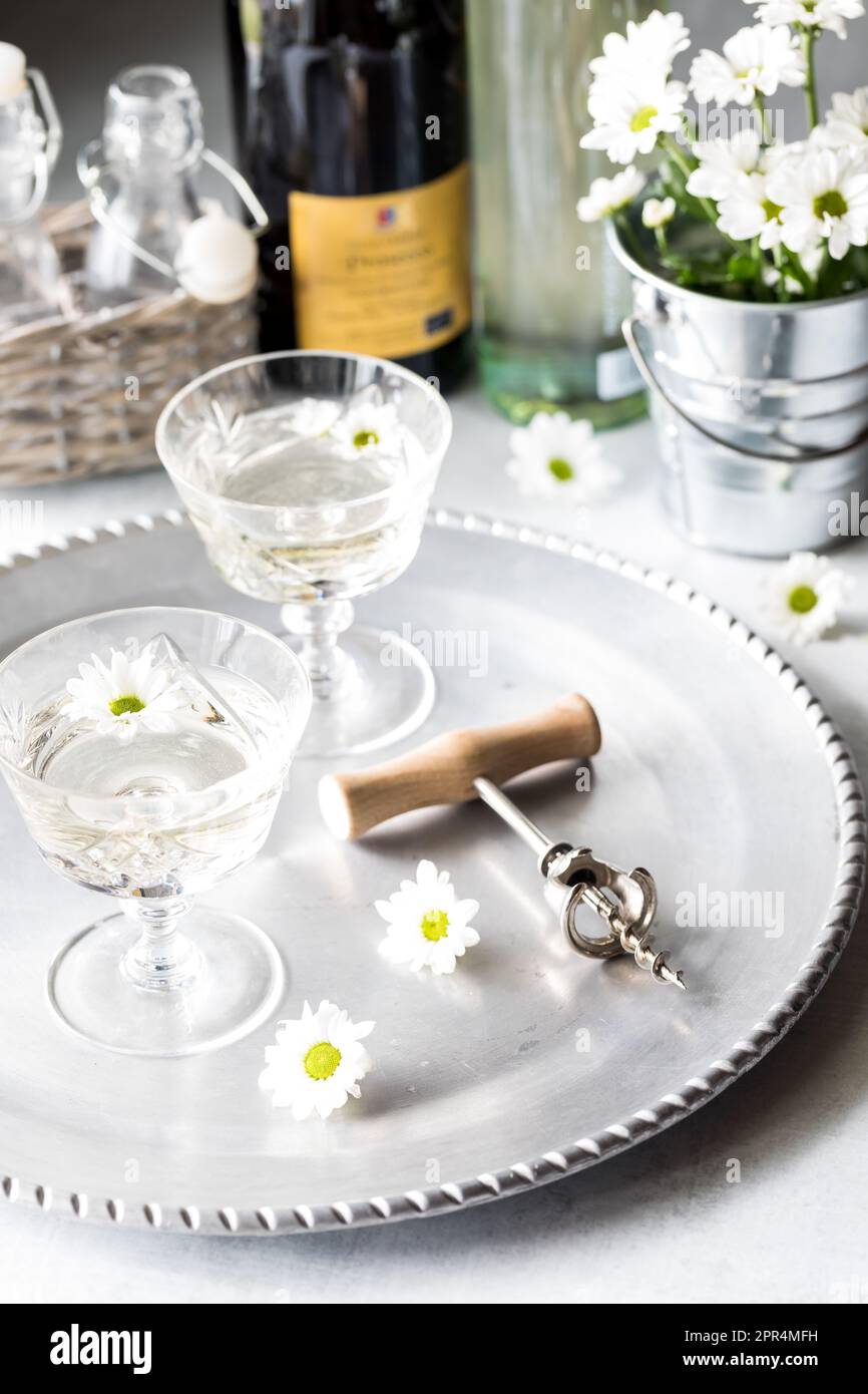 verres de vin blanc sur un plateau argenté garni de fleurs blanches. Banque D'Images