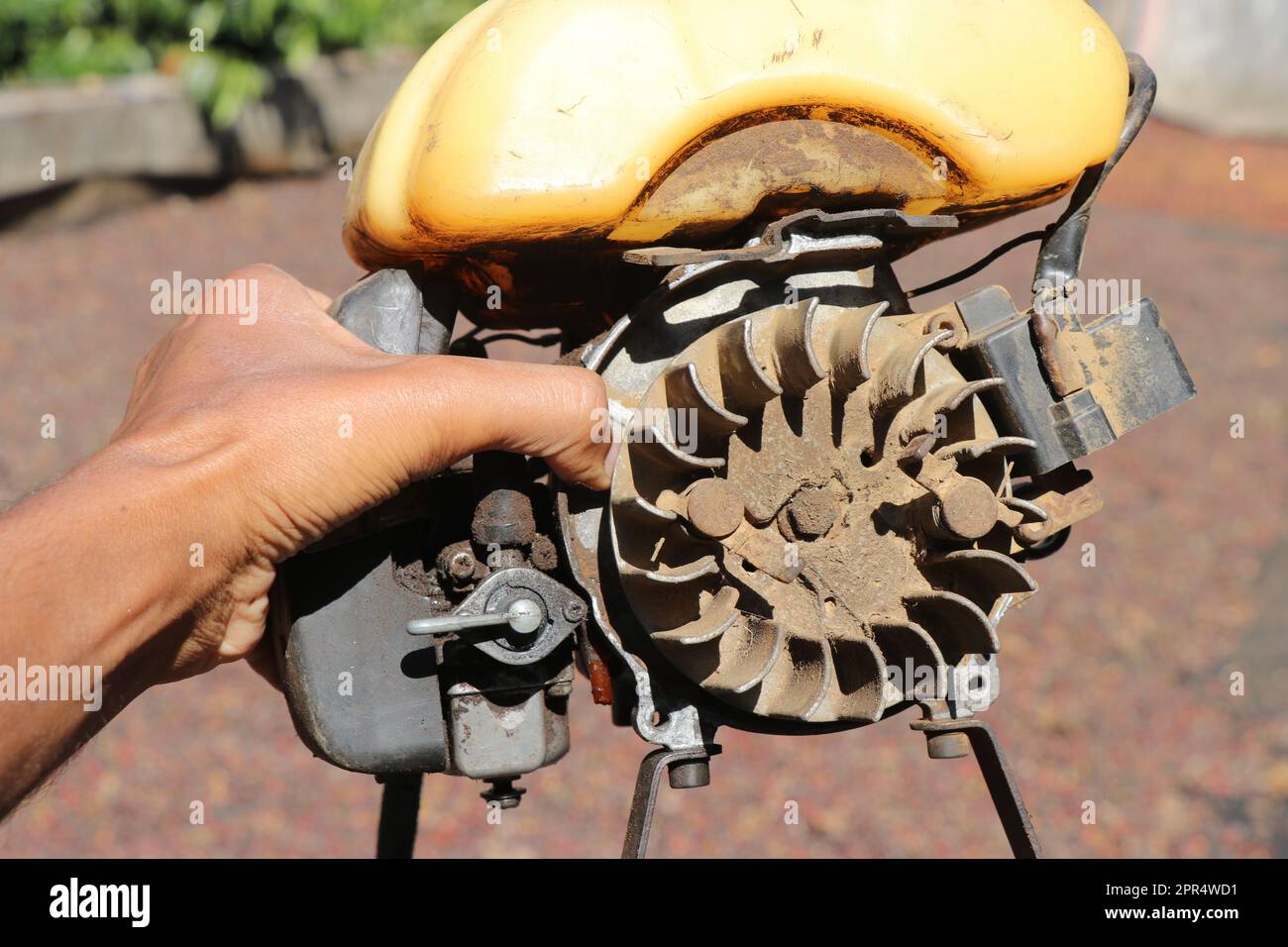 Volant d'un petit moteur à essence utilisé sur un couteau à brosse tenu dans la main. Parties du réservoir d'essence et du carburateur du coupe-herbe à essence Banque D'Images