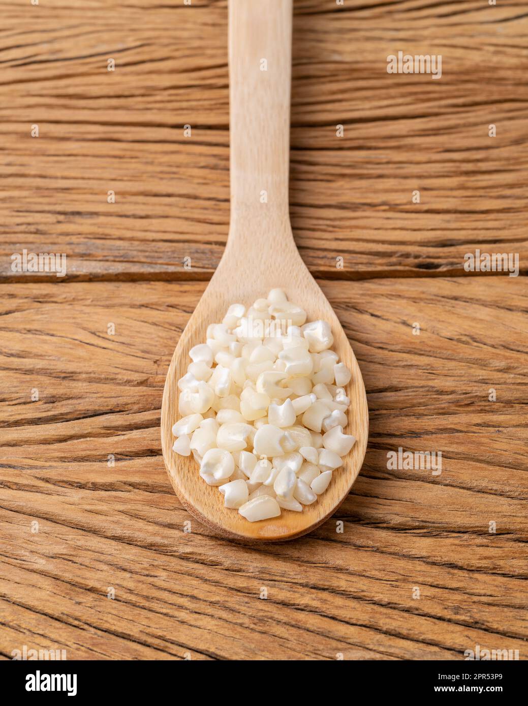 Canjica séché, maïs hominy ou blanc dans une cuillère sur une table en bois. Banque D'Images