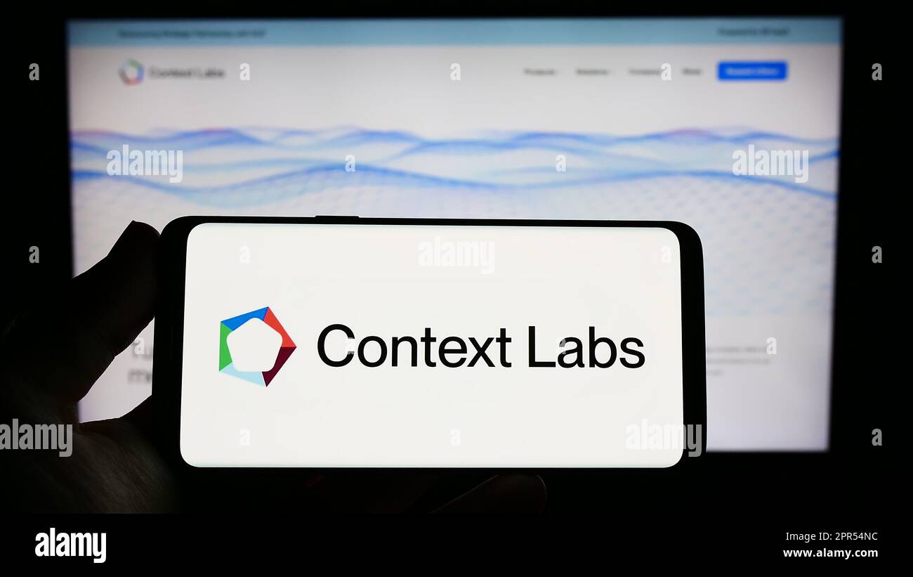 Titulaire d'un smartphone portant le logo de la société hollandaise de blockchain Context Labs B.V. (CXL) à l'écran devant le site Web. Mise au point sur l'affichage du téléphone. Banque D'Images